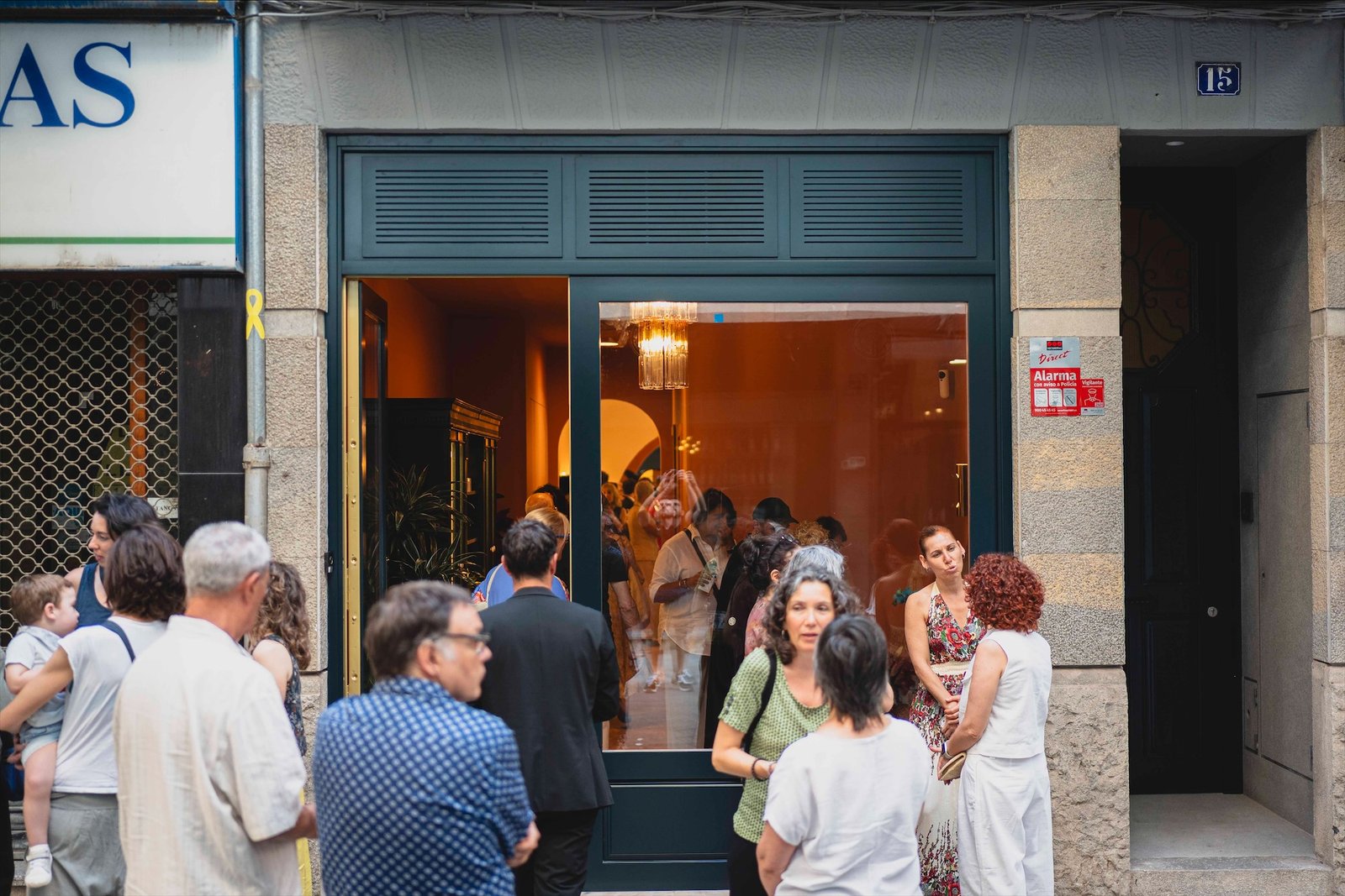 Invitados en la puerta de la calle, con el interior iluminado