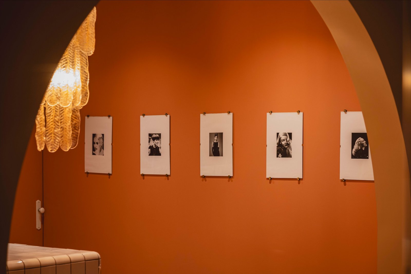 Cinco fotografías en blanco y negro en la pared, bajo la lámpara
